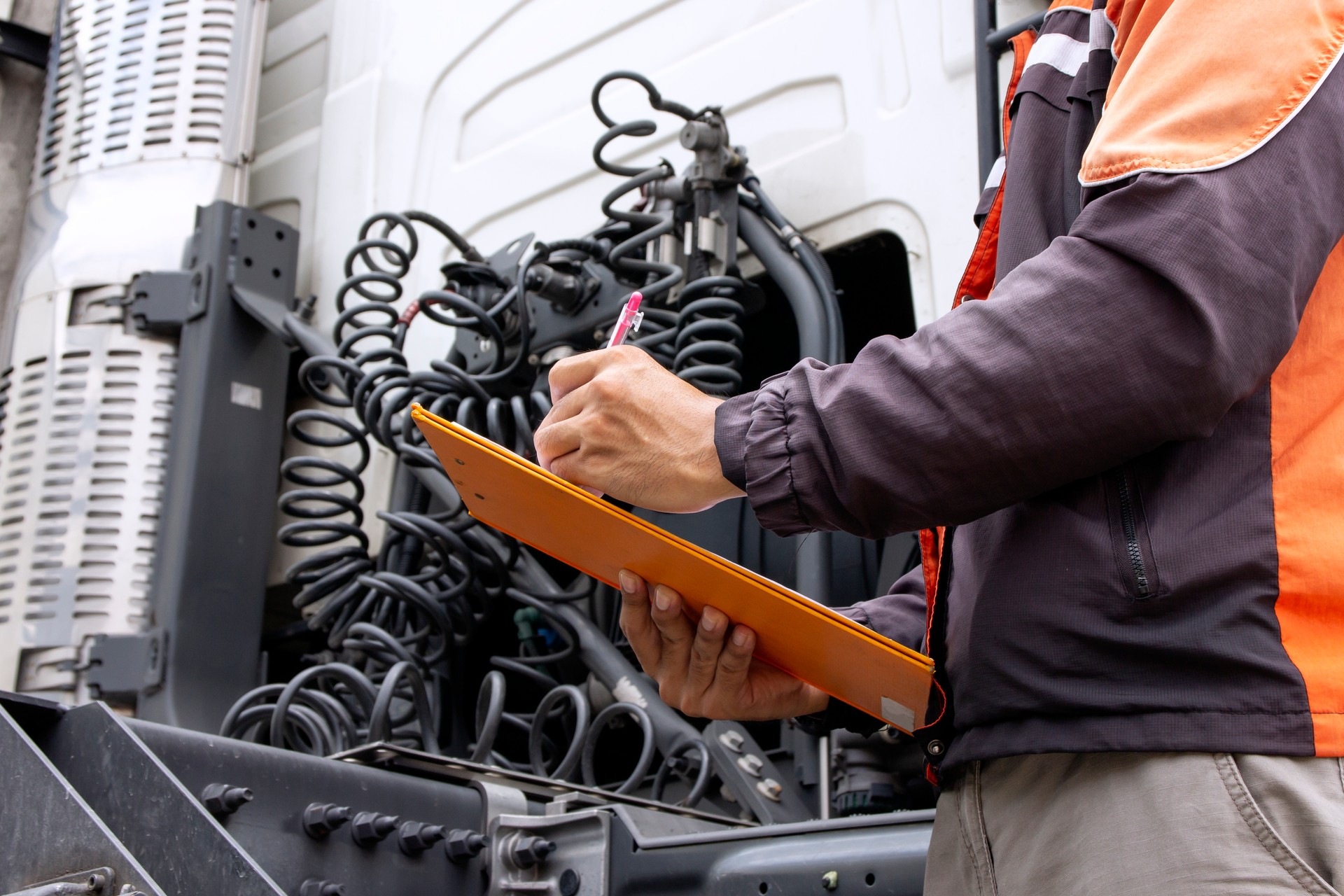 Truck driver holding clipboard inspecting safety daily check the engine of semi truck